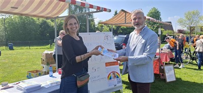 Femke de Jong overhandigd stripboek "Scholly de Scholver" aan wijkwethouder Cor Schaatsbergen tijdens koningsdagbraderie bij buurthuis 't Klavier.