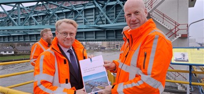 Minister Robert Tieman ontvangt rapportage Staat van de infrastructuur Rijkswaterstaat op de Algrabrug uit handen van directeur-generaal Martin Wijnen.