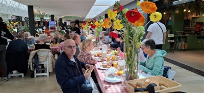 Buurtbewoners en bezoekers genieten van een gratis verzorgde lunch in winkelcentrum de Koperwiek.